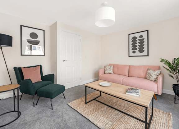 A living room with a pink couch, green chair, and a coffee table at Origins Apartments, Cambridge, CB3 0UX