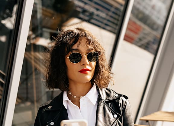 A woman in a black leather jacket is looking at her phone.