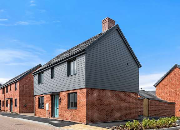 A modern house with a grey facade and a brick wall.