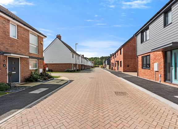 A residential street with houses on both sides and a clear blue sky.