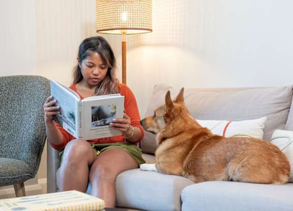 Woman reading book with dog sitting beside her at The Lark, London, SW11 7EA