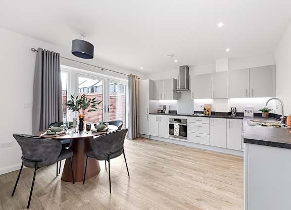 A modern kitchen with a dining table set for two at The Woodlands Apartments, Milton Keynes