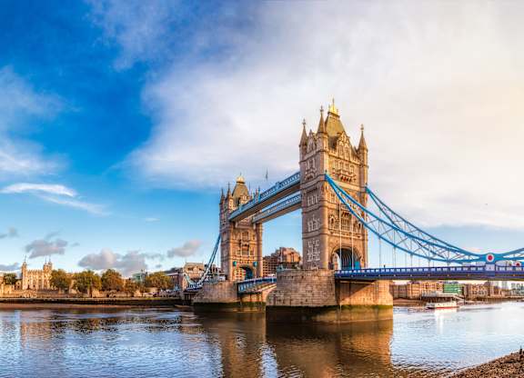 A large blue bridge with a golden top spans a body of water.