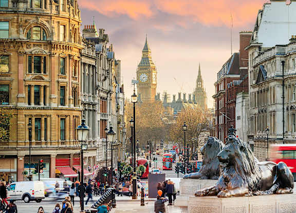 A lion statue is in the middle of a busy street.