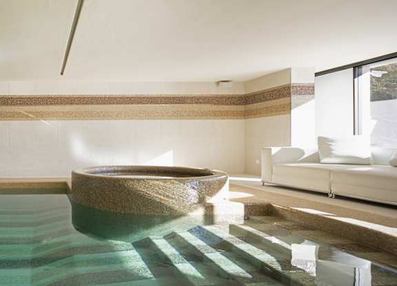 A large indoor swimming pool with a hot tub in the middle.