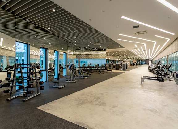 A gym with a variety of equipment and a large mirrored wall.