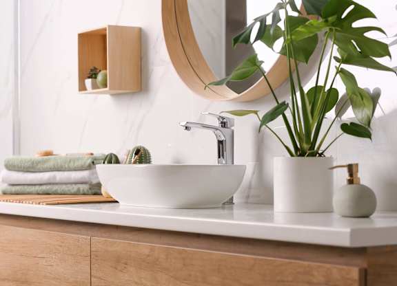 A bathroom with a white sink and a round mirror.