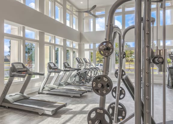 a gym with cardio equipment and windows in a building