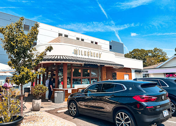 A black car is parked in front of a building with a sign that reads "Mulberry.".