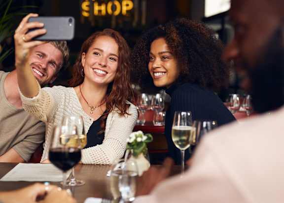 Three people are sitting at a table, laughing and enjoying a meal together.