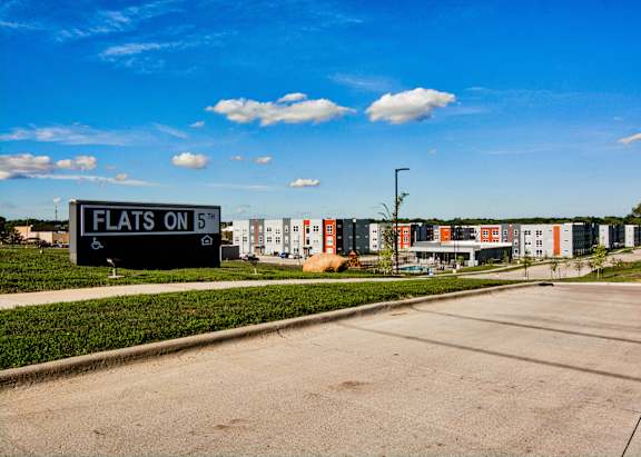 A sign that says "FLATS ON B" is in front of a building.
