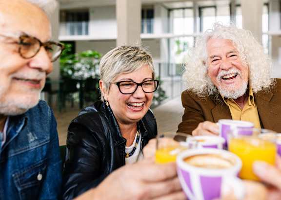 Three people are sitting at a table with cups of coffee and orange juice.