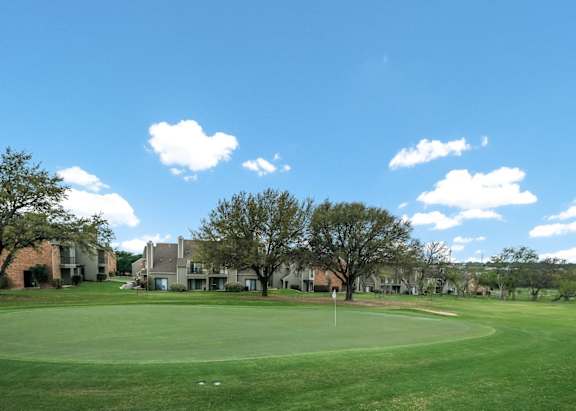 A golf course with a clear blue sky and a few clouds.