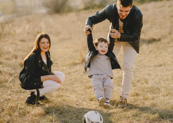 a man and woman playing with a child on a field