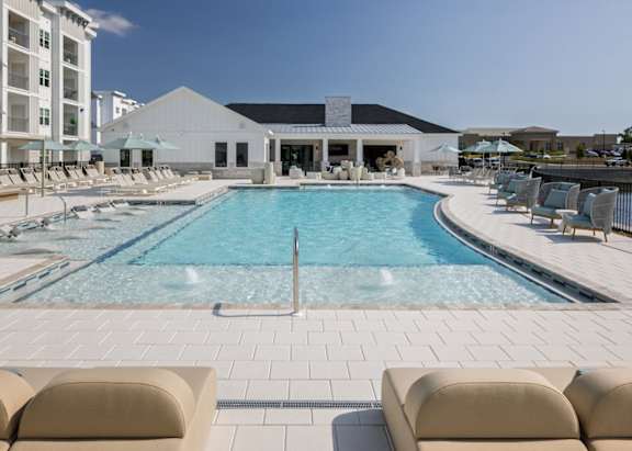 A large pool surrounded by white lounge chairs and palm trees.