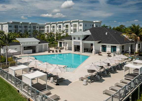A large pool surrounded by white lounge chairs and palm trees.