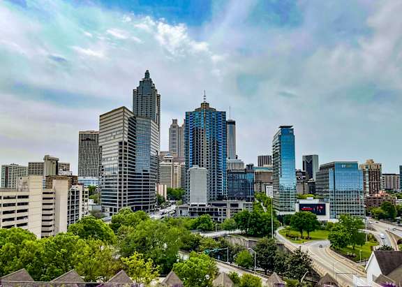A cityscape with tall buildings and a cloudy sky.