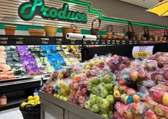 A produce section in a store with a red umbrella overhead.