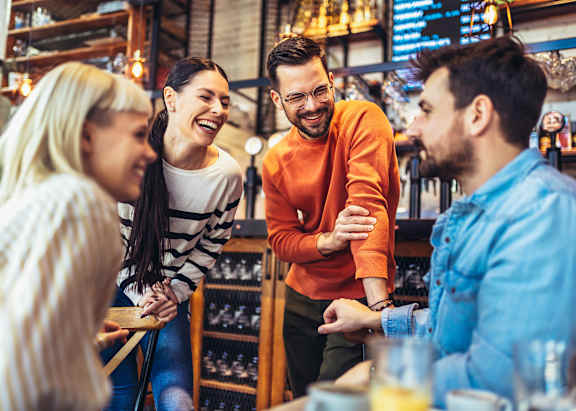 Four people are sitting at a table in a bar.
