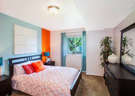 A bedroom with a bed, nightstands, and a window.