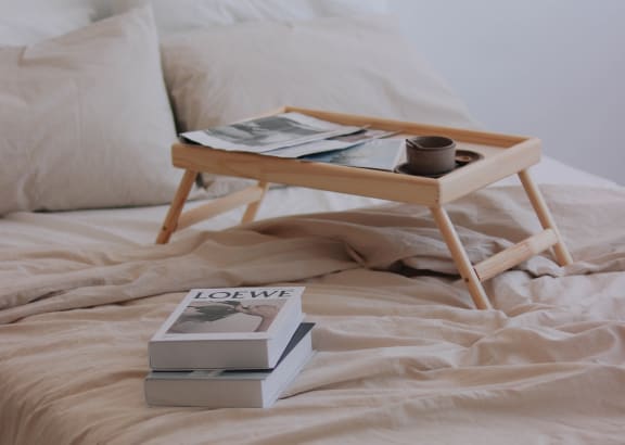 a tray on a bed with books and a cup of coffee