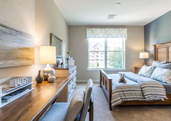 A bedroom with a bed, nightstand, and a painting on the wall.