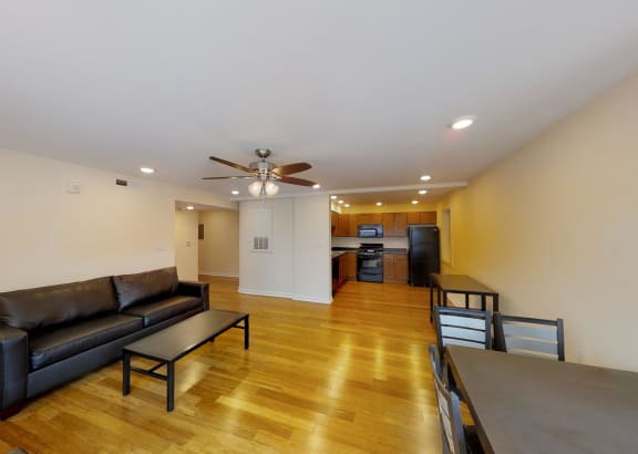 a living room with leather couches and a dining room table and a kitchen