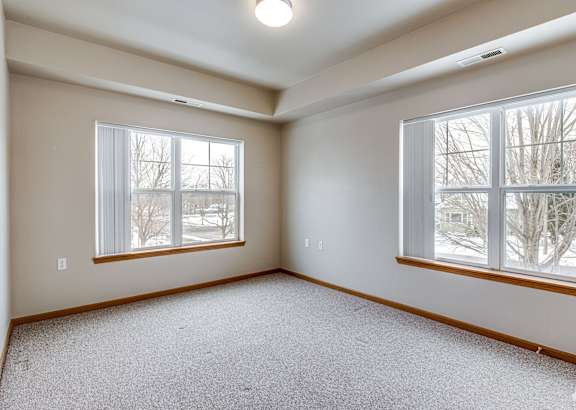 Empty room with two windows and carpeted floor.