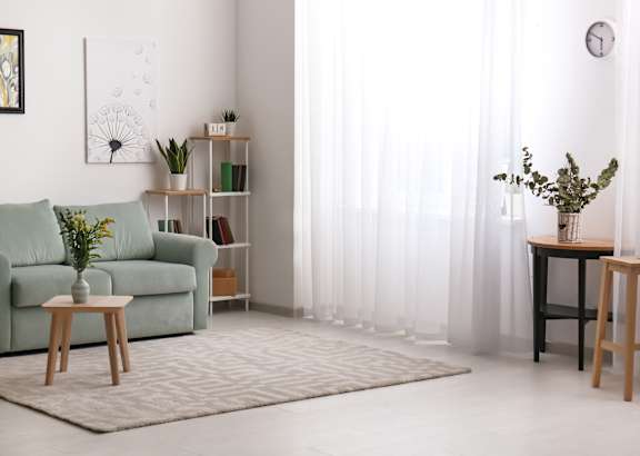 A living room with a green couch, a wooden table, and a painting on the wall.