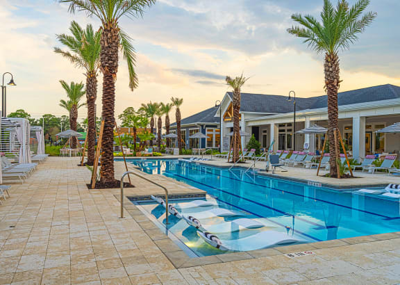 a resort style pool with lounge chairs and palm trees