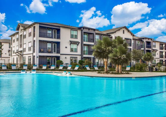 a large swimming pool with apartment buildings in the background