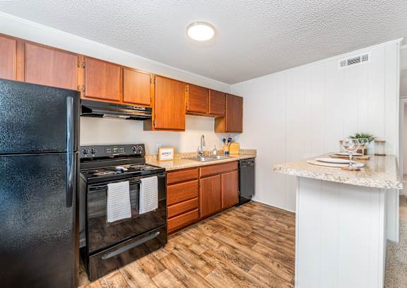 A black stove and oven in a kitchen with wooden floors and white walls.