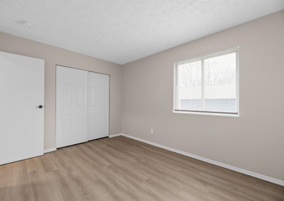 A room with a white door and a window with white blinds.