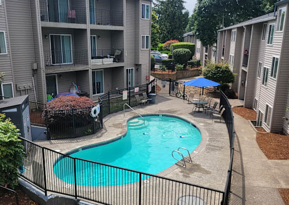 A black fence surrounds a small pool in a courtyard.