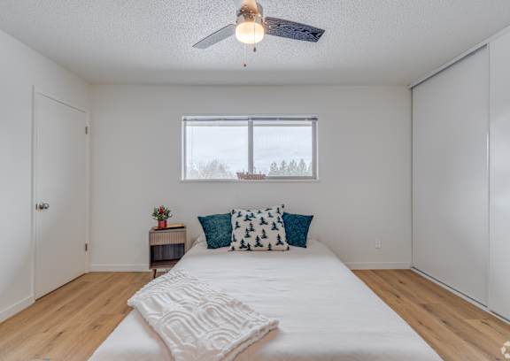 A bedroom with a bed, pillows, and a ceiling fan.