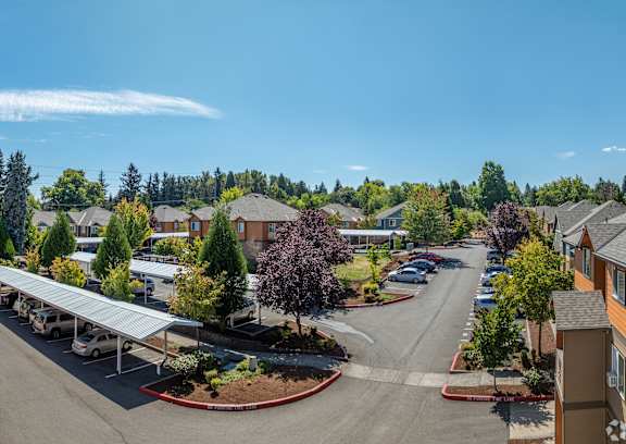 A sunny day at a residential complex with a parking lot in the foreground.