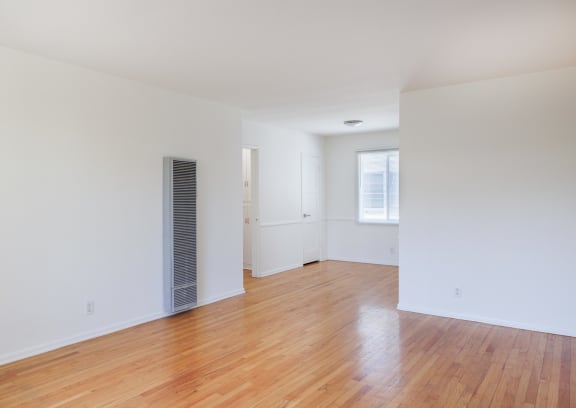 an empty living room with wood floors and white walls