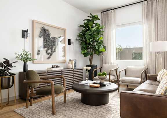 A living room with a brown leather couch, a coffee table, and a large painting on the wall.