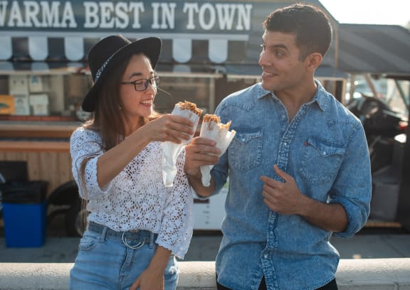 a man and a woman eating sandwiches at a food truck