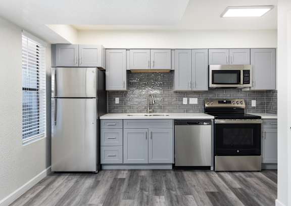 A kitchen with a refrigerator, microwave, oven, and sink.