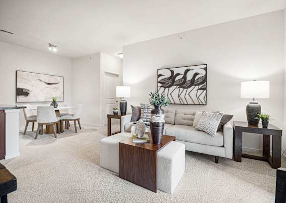 A living room with a white couch, a coffee table, and a painting on the wall.