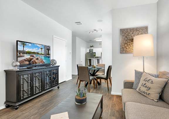 A living room with a grey couch, a wooden table, and a painting on the wall.