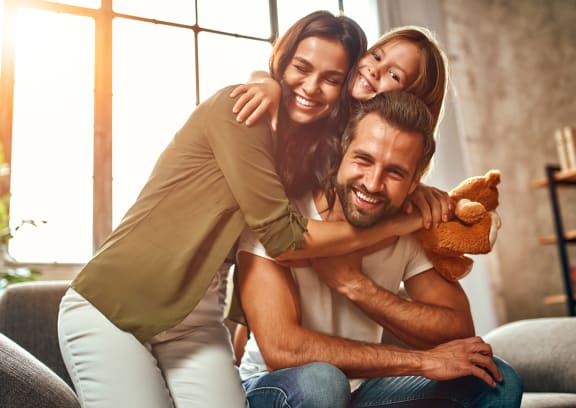 a man and two women sitting on a couch with a teddy bear