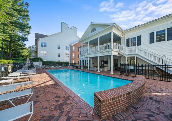 a swimming pool with umbrellas and chairs in front of a house at Sterling Manor, Virginia