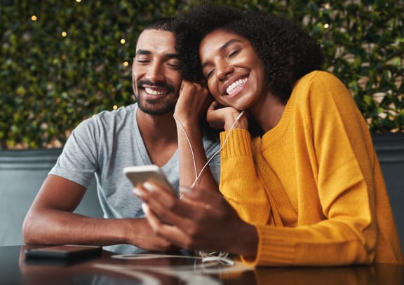 a couple sitting at a table looking at a cell phone