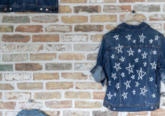 two denim jackets hanging on a brick wall