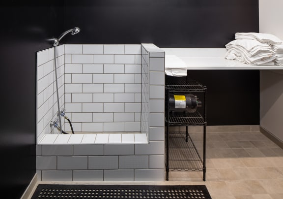 A bathtub with white tiles and a shelf with towels at Mercantile on Broadway, Fargo, ND 58102