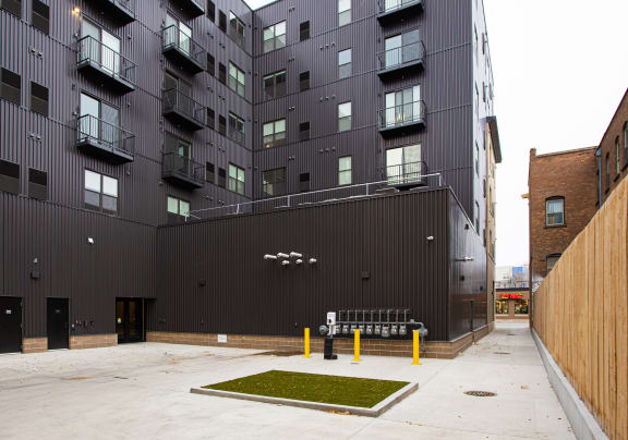 A courtyard with a bench and grass patch in front of a black building at Mercantile on Broadway, Fargo, ND 58102