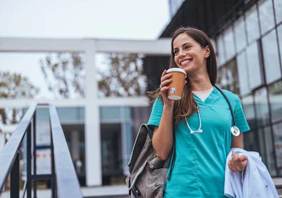 A woman in a teal scrub top is holding a coffee cup and a jacket.at SoRoc On Maine, Minnesota, 55904