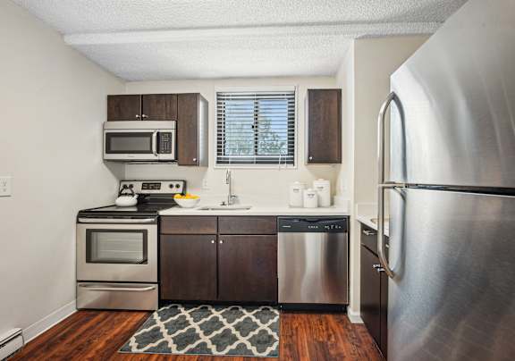 A kitchen with a stainless steel refrigerator, microwave, oven, and sink.